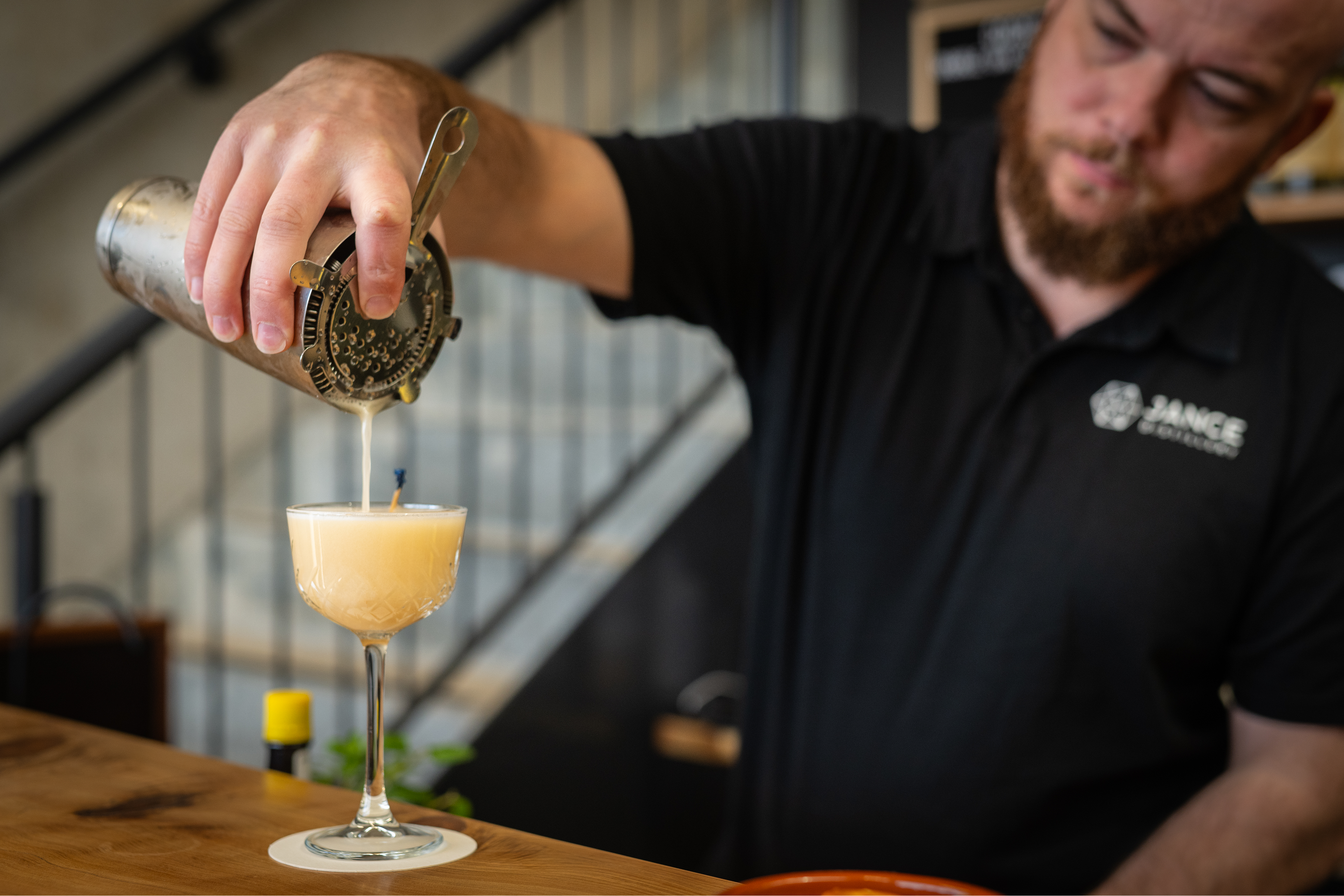 Man pouring a cocktail into a glass with a blurred background